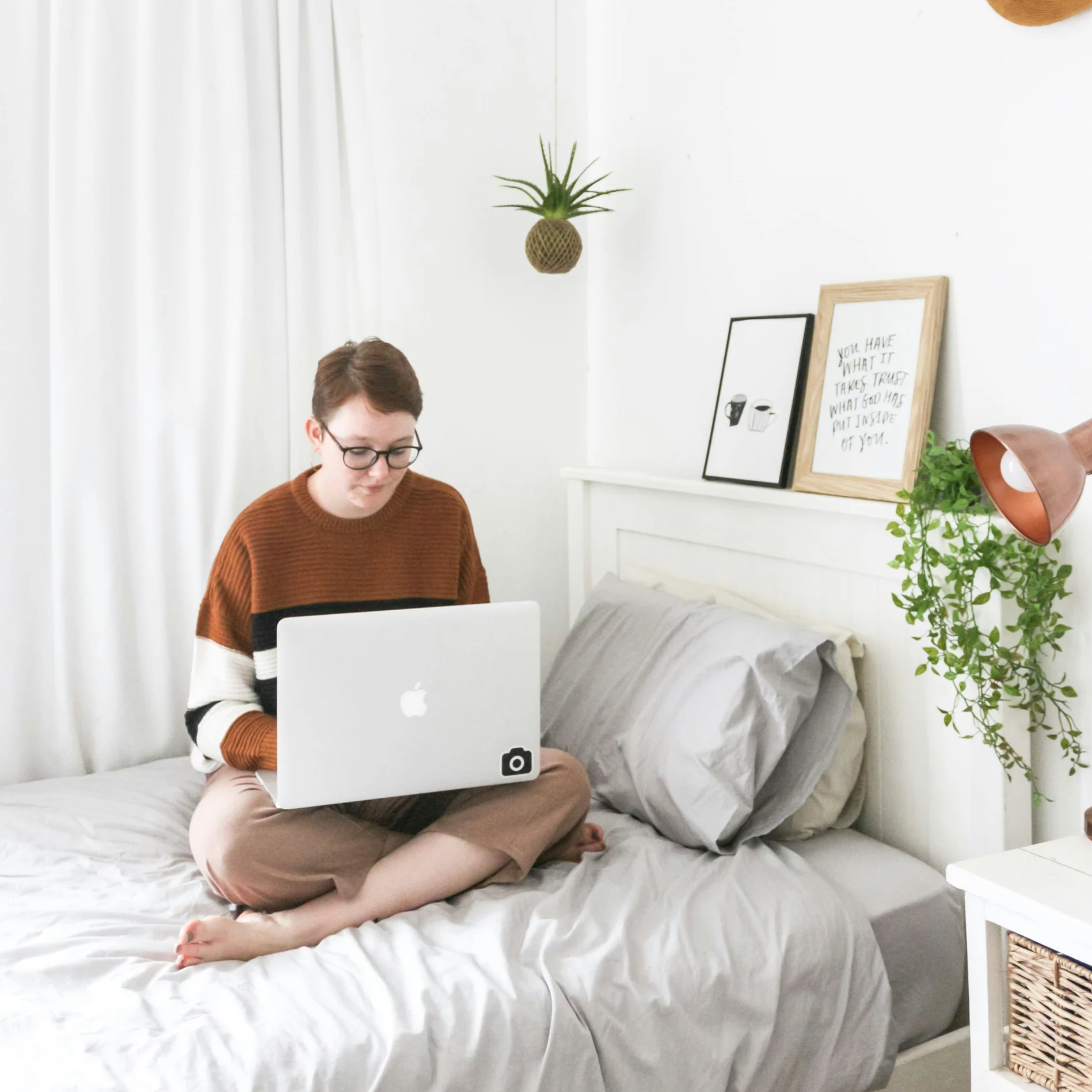 a women sitting on her bed, with her laptop